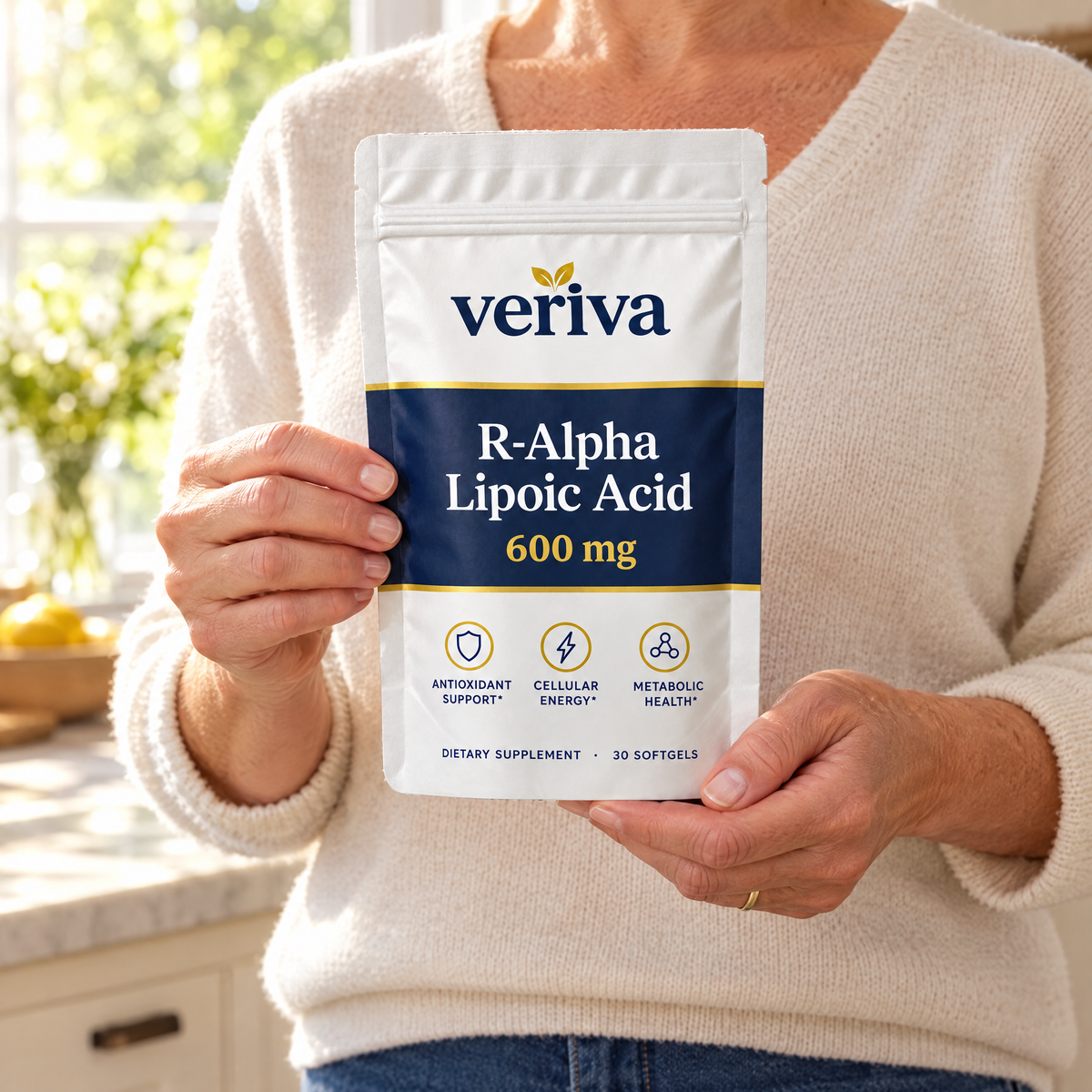 Hands holding a Veriva pouch in a sunlit kitchen